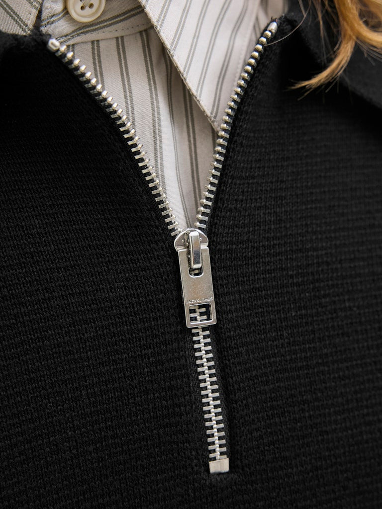 Close-up of a black polo with a silver zipper