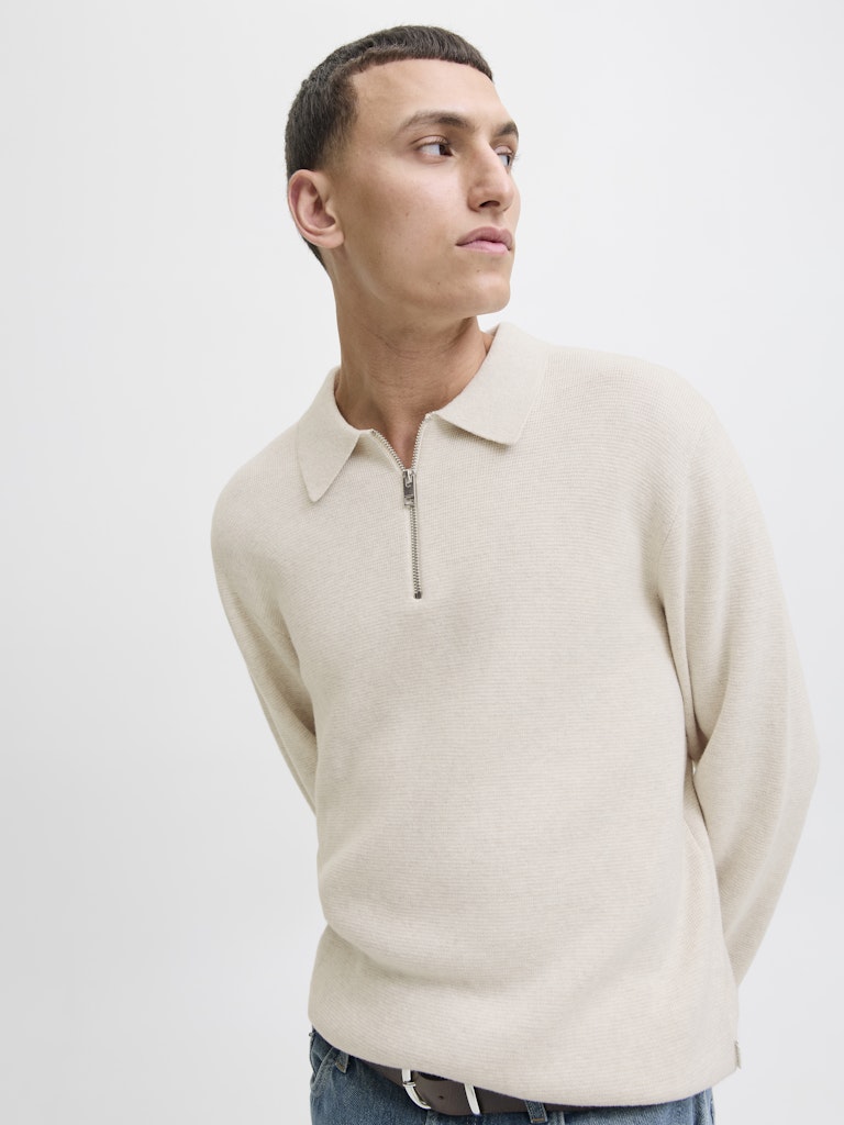 Man wearing a beige sweater with a zipper on a white background