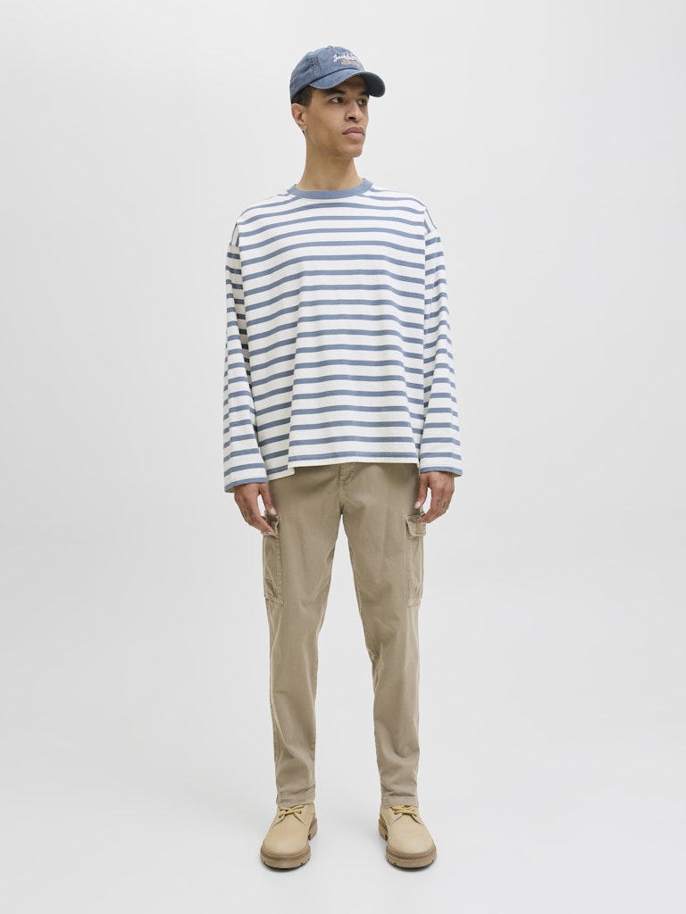 Person wearing a striped shirt, cap, and beige pants on a white background