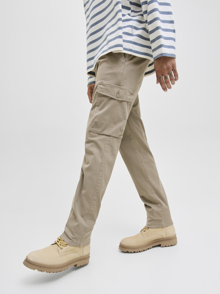 Person wearing beige cargo pants and boots on a white background