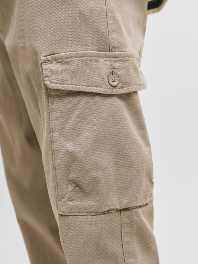 Close-up of beige cargo pants with a pocket on a light gray background