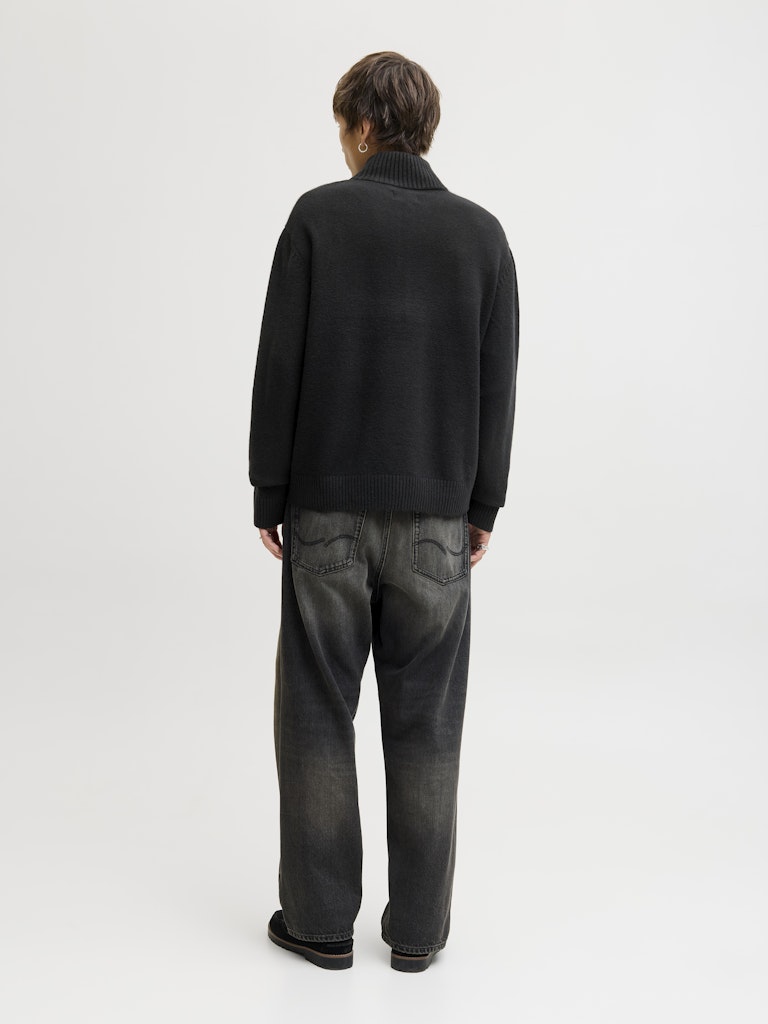 Person wearing a black jumper and gray pants on a white background
