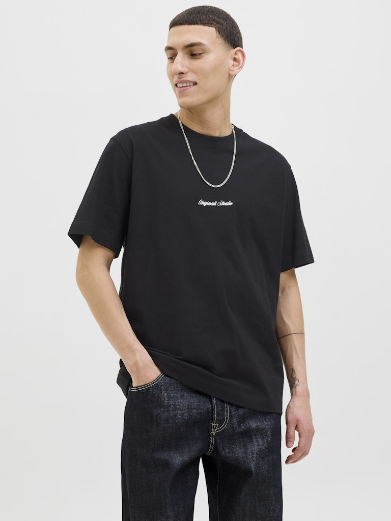 Person wearing a black t-shirt with white text and dark jeans on a light gray background