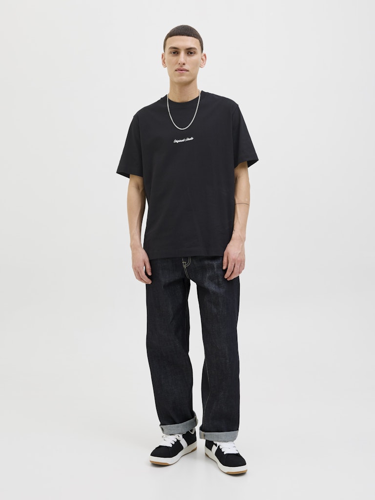 Person wearing a black t-shirt and dark jeans on a white background
