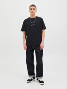 Person wearing a black t-shirt and dark jeans on a white background