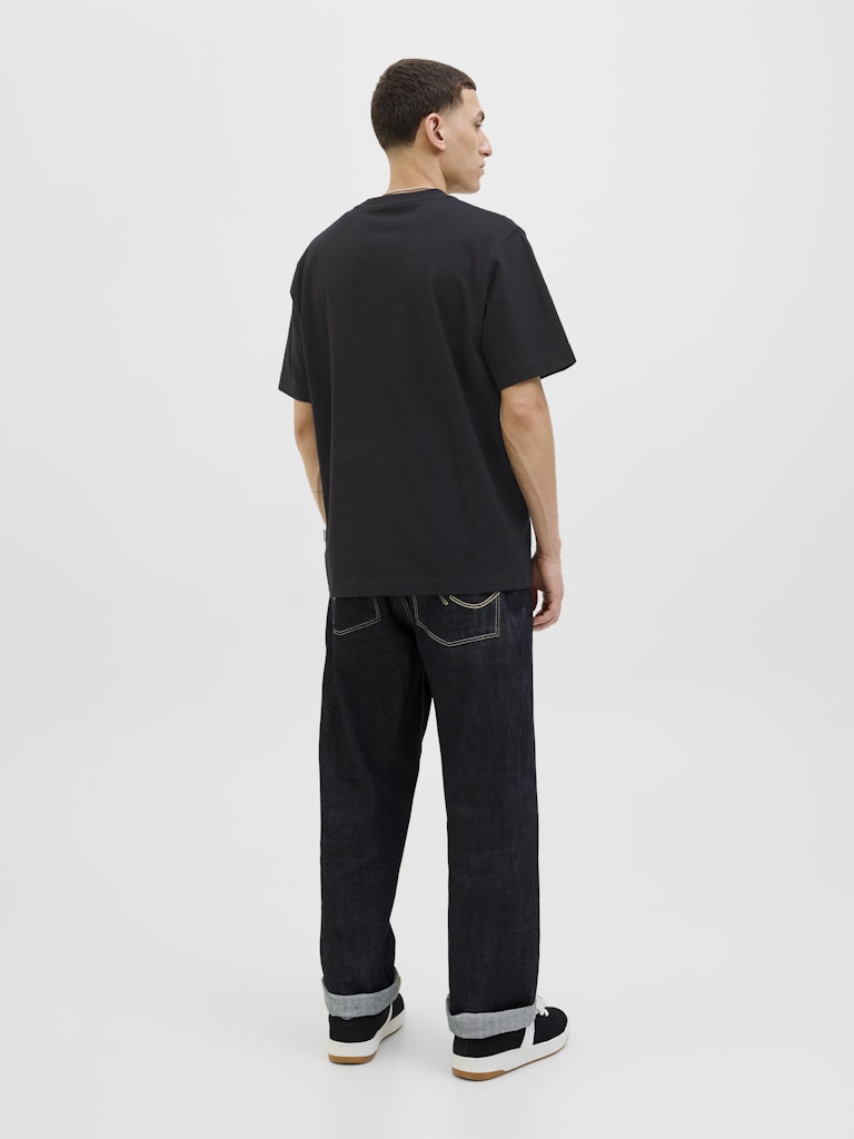 Person wearing a black t-shirt and dark jeans on a white background