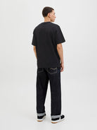 Person wearing a black t-shirt and dark jeans on a white background