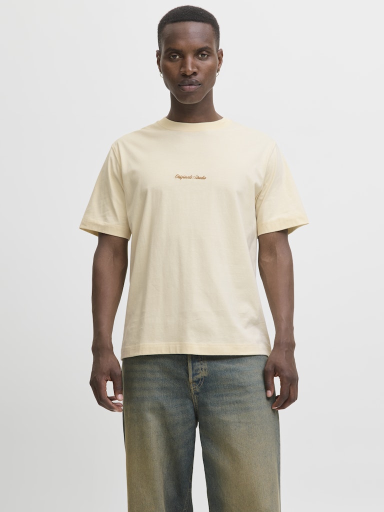 Man wearing a beige t-shirt with text and jeans on a white background
