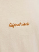 Embroidered text 'Originals Studio' on a beige tee