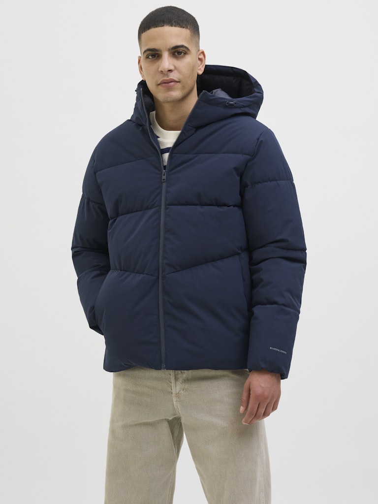 Man wearing a navy blue puffer jacket on a white background