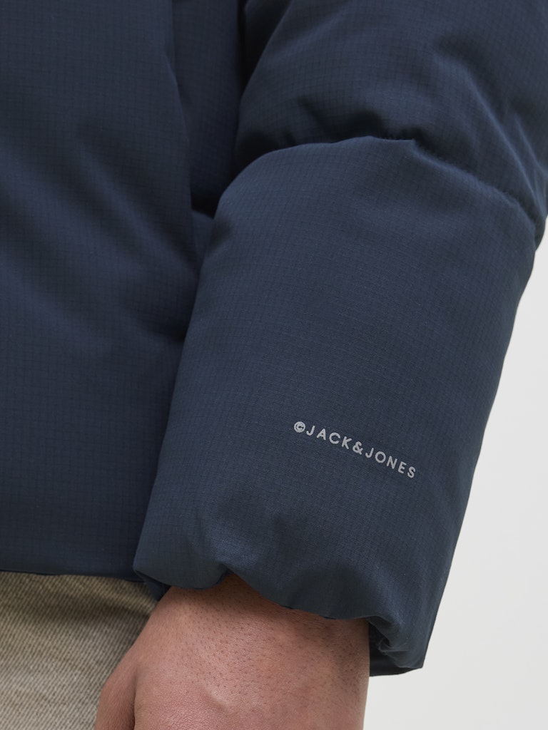 Close-up of a navy blue sleeve with 'Jack & Jones' logo on a light gray background