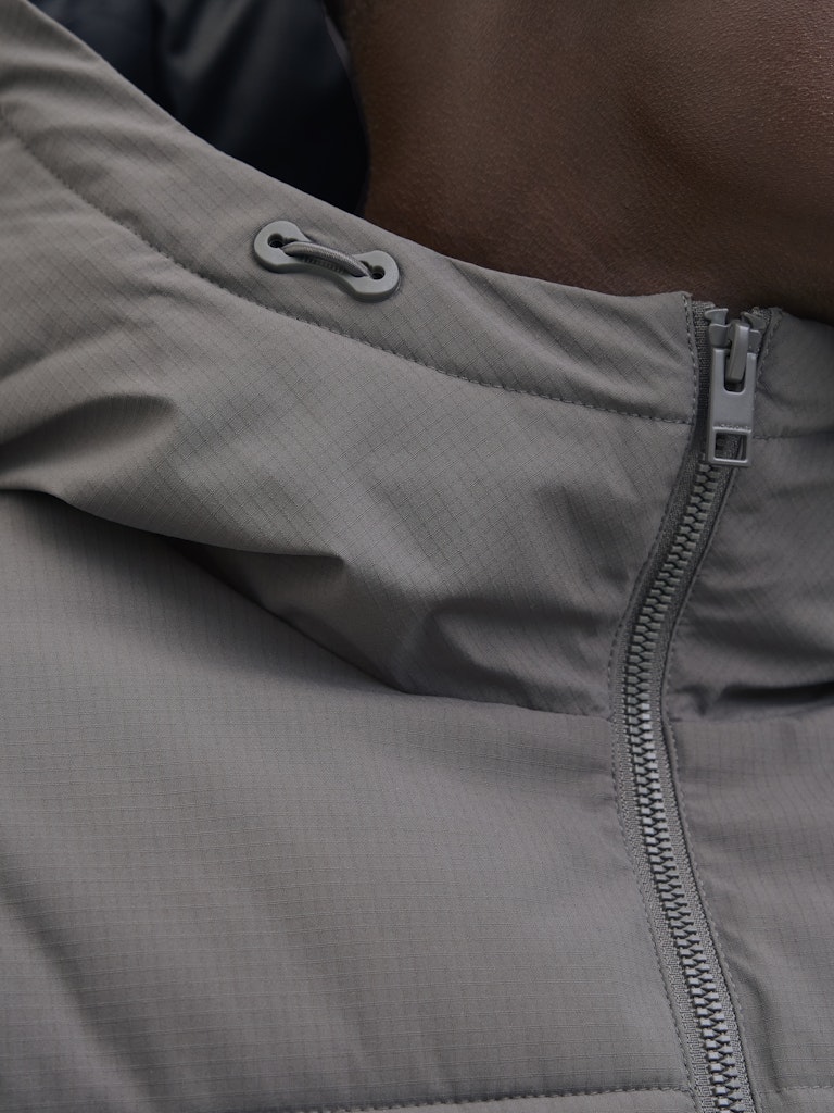 Close-up of a gray jacket with zipper and button details