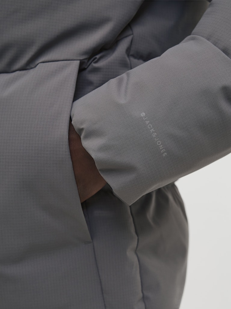 Close-up of a gray jacket with a brand logo on a light gray background