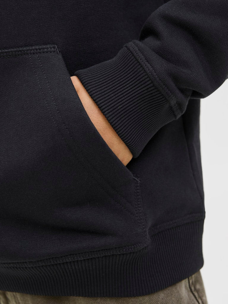 Close-up of a black hoodie with a pocket and sleeve detail on a neutral background