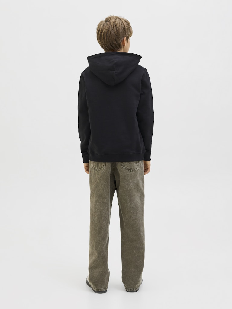 Boy wearing a black hoodie and grey jeans on a white background