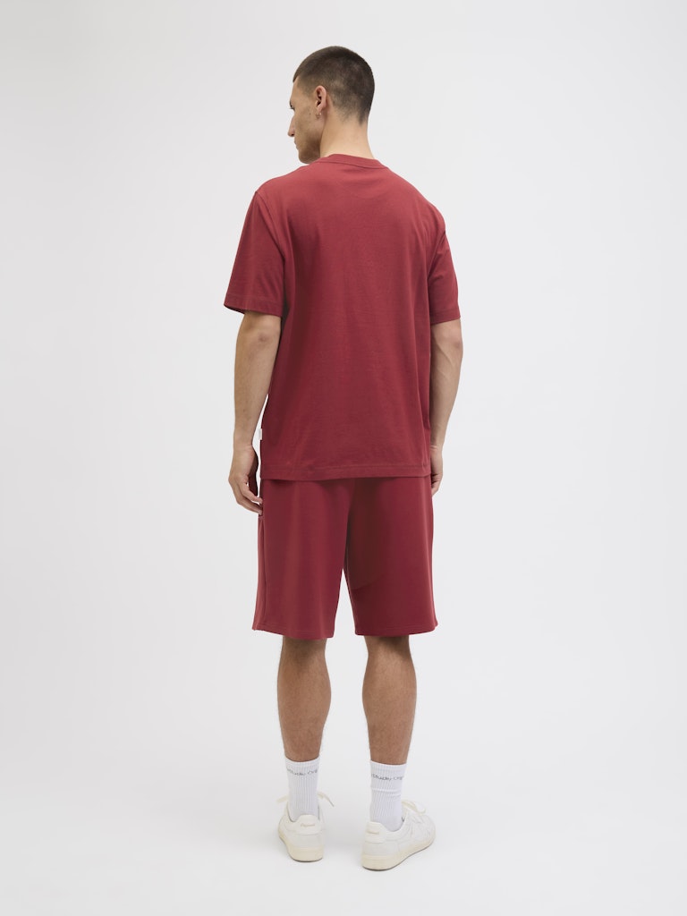 Man wearing a red t-shirt and shorts set on a white background