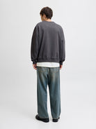 Man wearing a grey sweatshirt and blue jeans