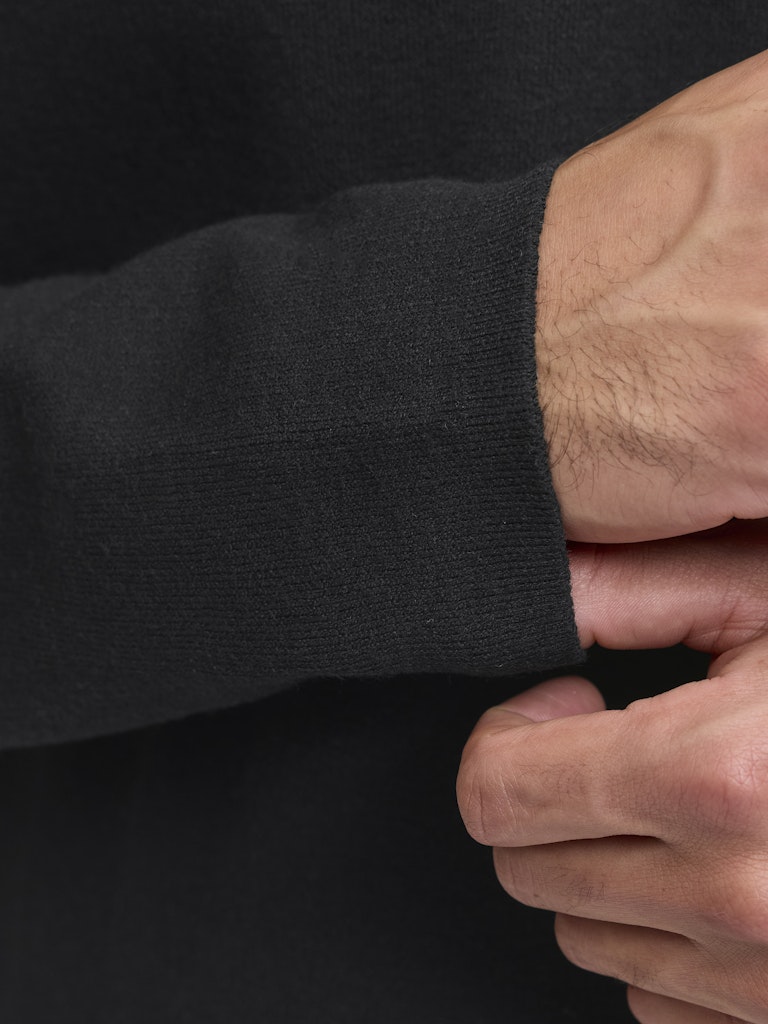 Close-up of a person wearing a black long-sleeve shirt with a focus on the sleeve and hand.