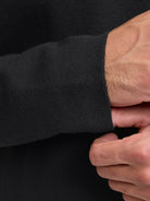 Close-up of a person wearing a black long-sleeve shirt with a focus on the sleeve and hand.