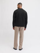 Man wearing a black sweater and beige pants on a white background