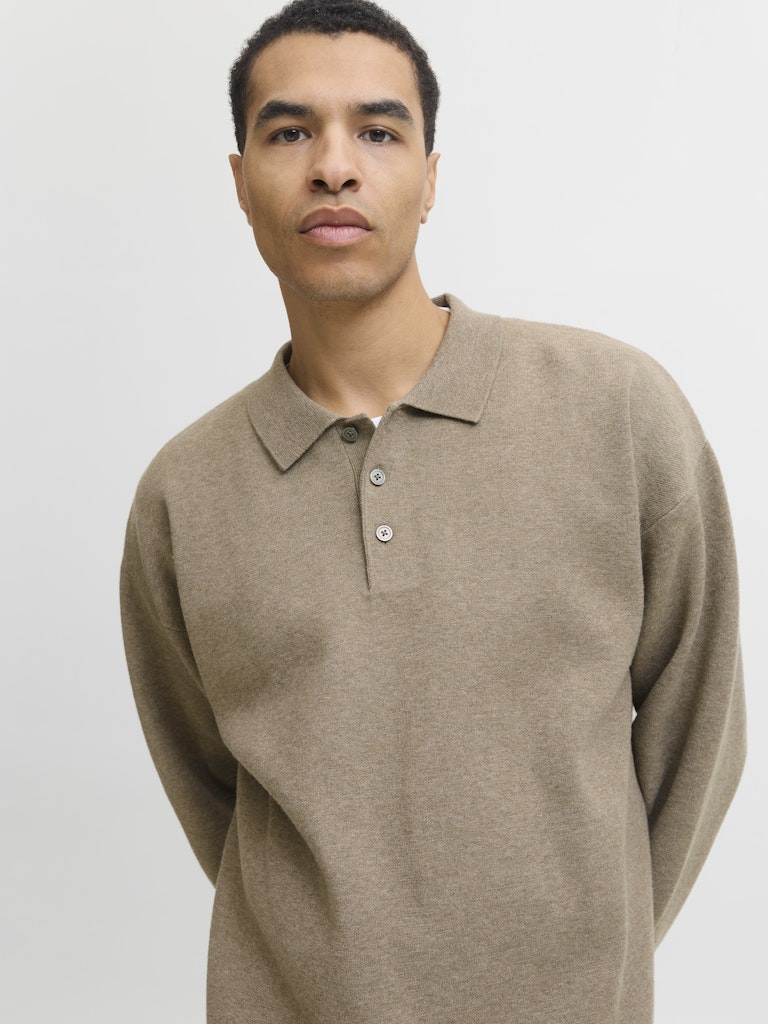 Man wearing a beige long-sleeve polo shirt against a plain background