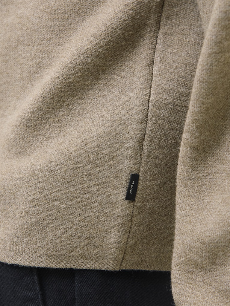 Close-up of a beige fleece jacket with a brand label on a dark background