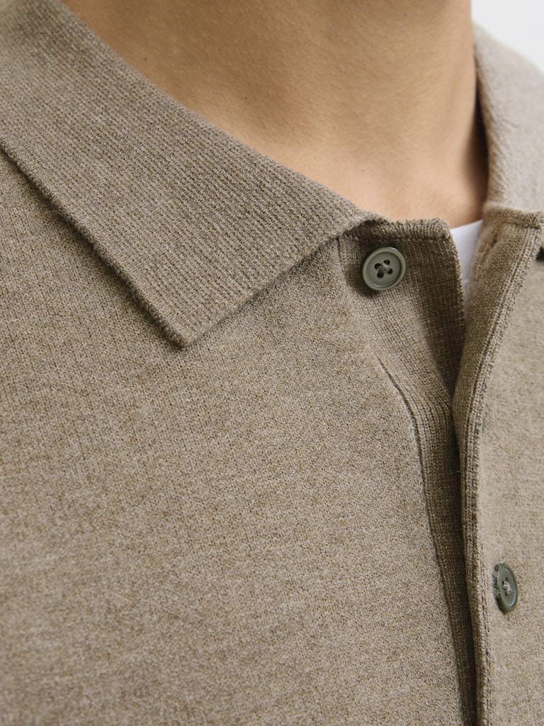 Close-up of a beige cardigan with a button on a neutral background