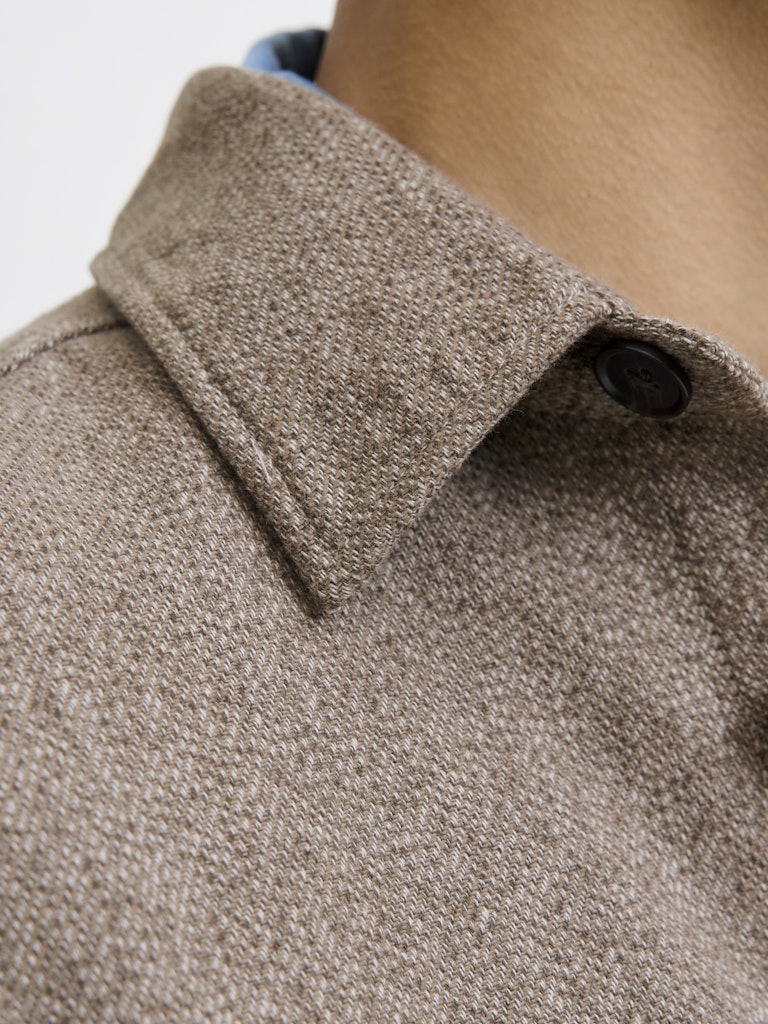 Close-up of a brown textured shirt collar on a light gray background
