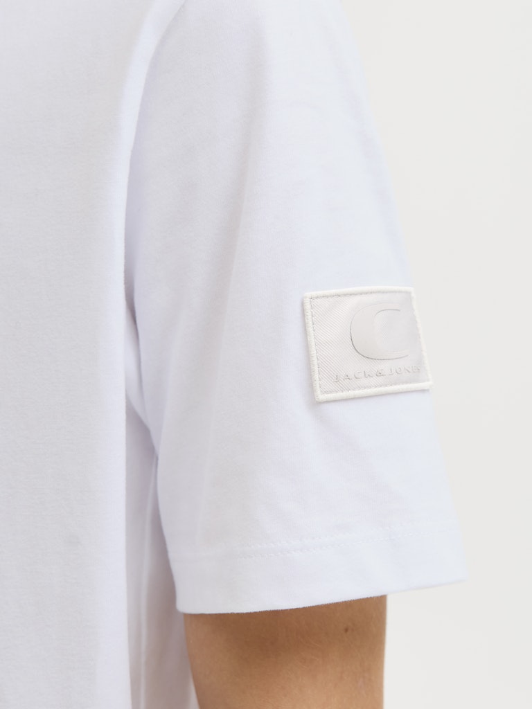Close-up of a white shirt with a brand logo on a light gray background