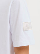Close-up of a white shirt with a brand logo on a light gray background