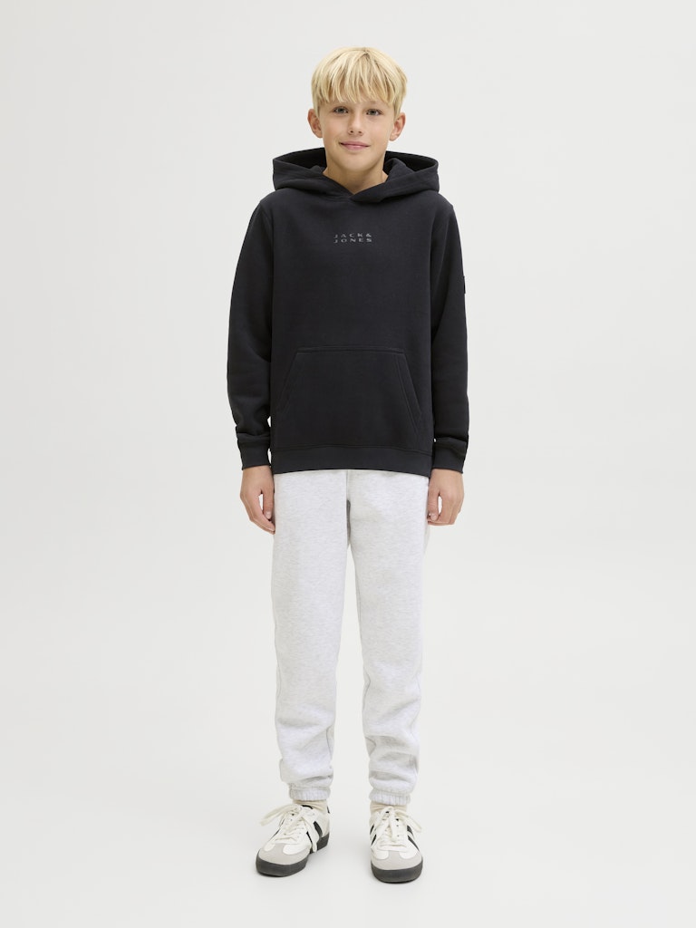 Child wearing a black hoodie and white pants on a white background