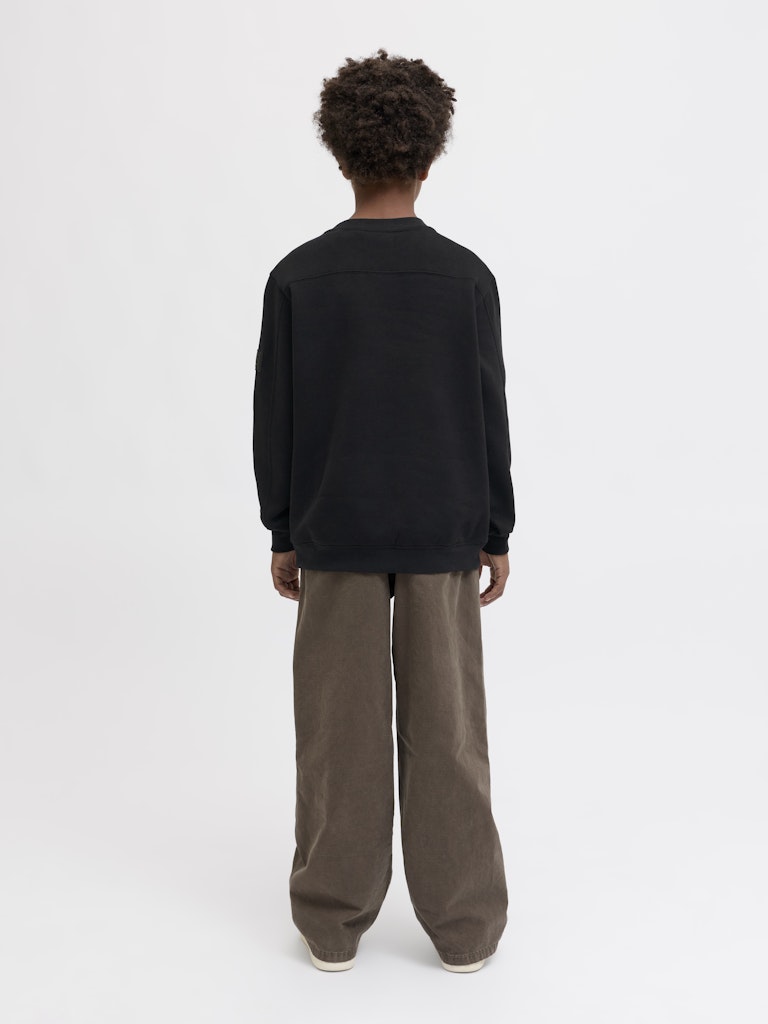 Person wearing a black sweater and brown pants on a white background