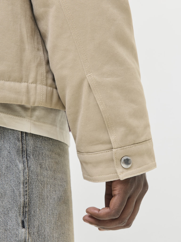 Close-up of a beige jacket with a button on a white background