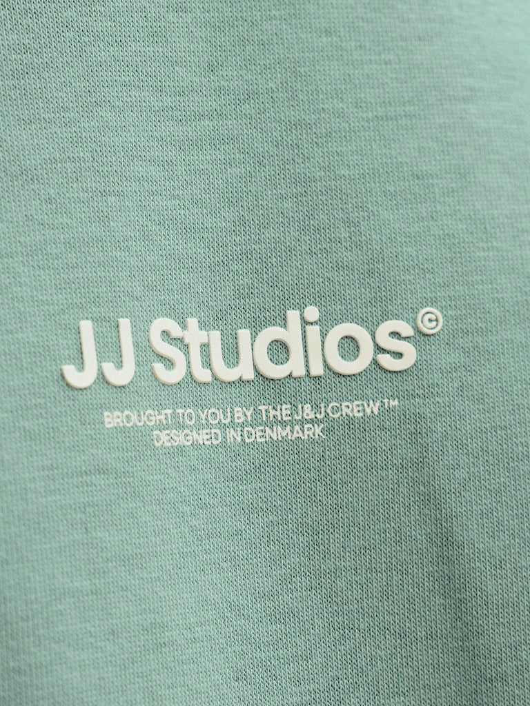 Close-up of a green fabric with 'JJ Studios' logo and text.