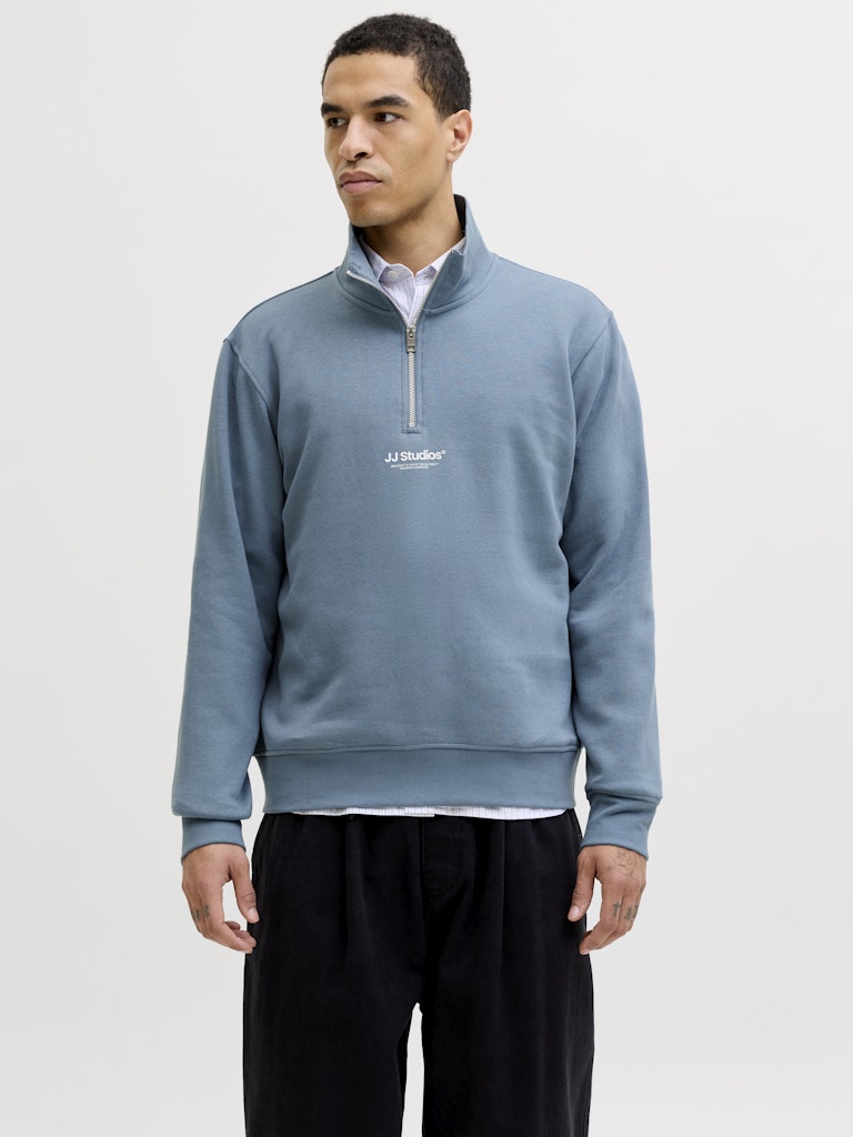 Man wearing a blue pullover with a logo on a white background