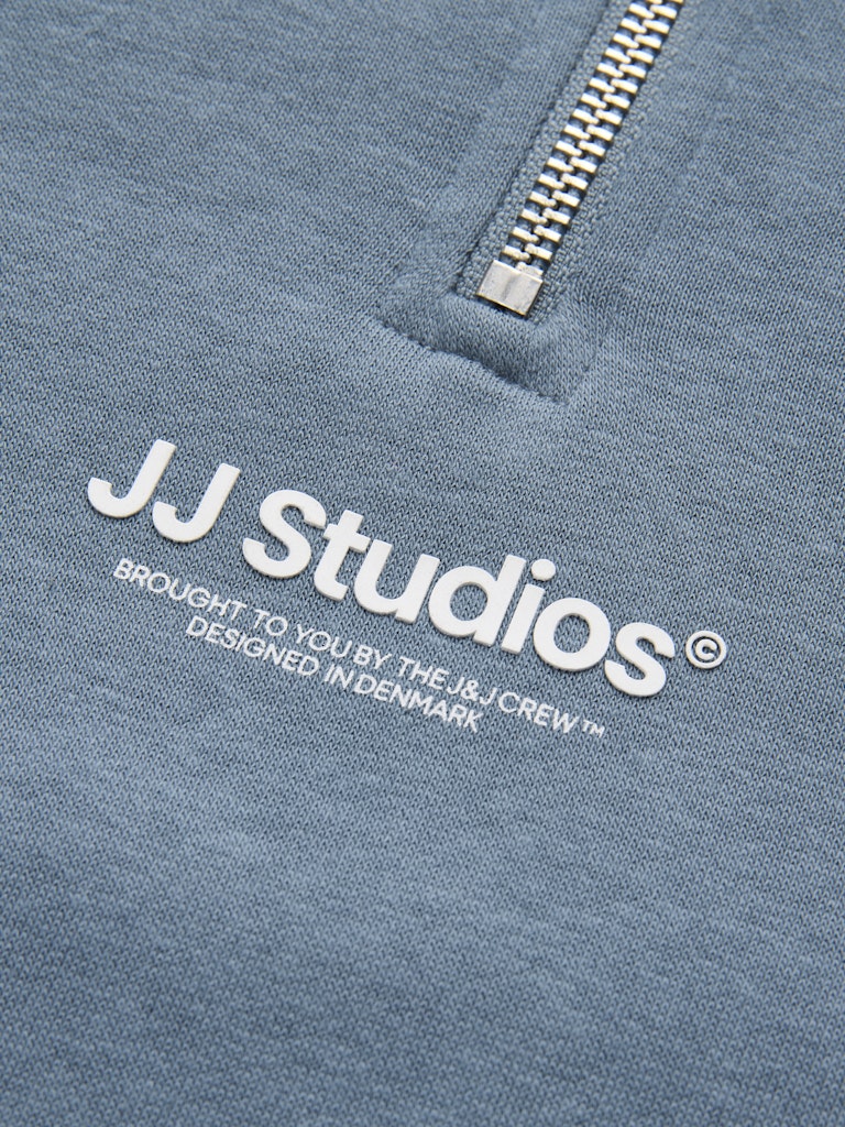 Close-up of a blue sweatshirt with 'JJ Studios' logo and text.
