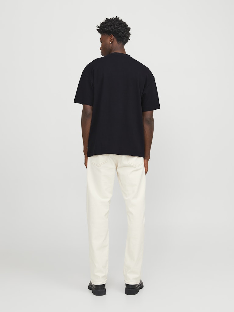Person wearing a black t-shirt and white pants on a plain background