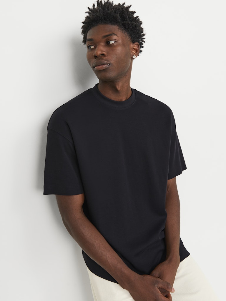 Person wearing a black t-shirt against a plain background