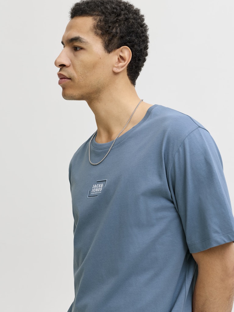 Man wearing a blue short sleeve tee with a jack & Jones logo on the chest-Side view