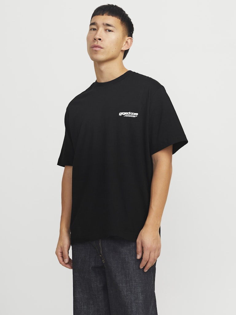 Person wearing a black t-shirt with a logo on a plain background