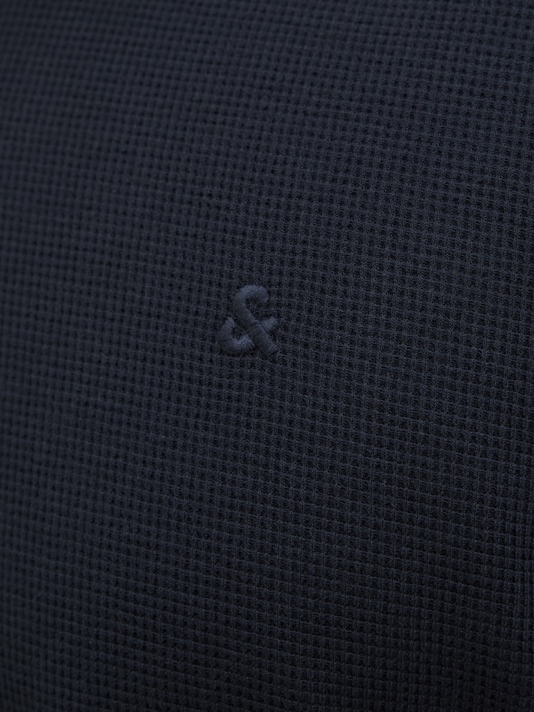 Close-up of a dark blue fabric with a small logo or brand emblem.