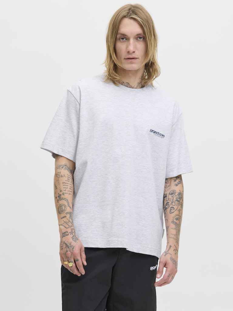 Person wearing a white t-shirt with a logo on a plain background