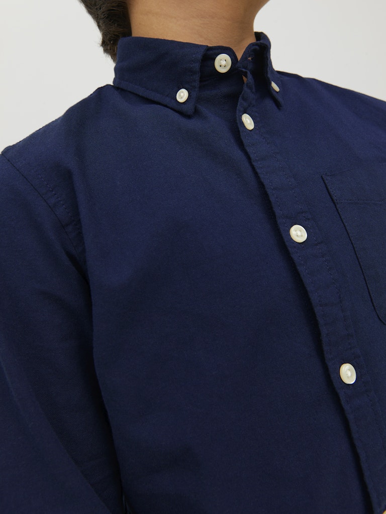 Navy blue shirt with white buttons on a plain background