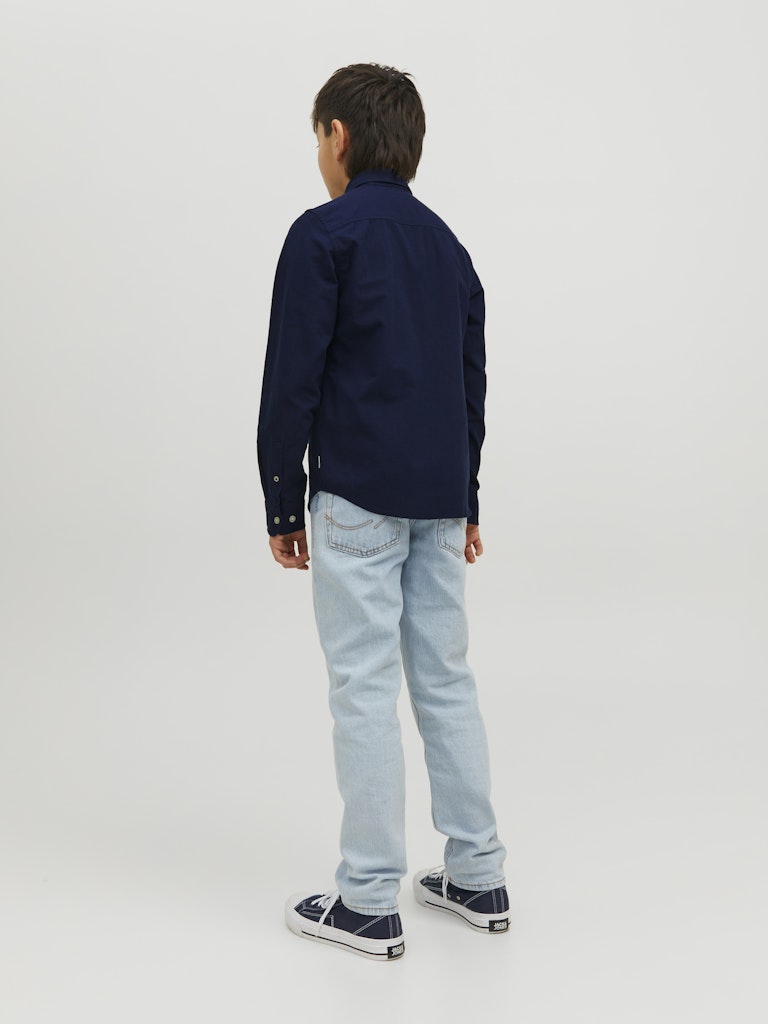Person wearing a navy shirt and light blue jeans on a white background