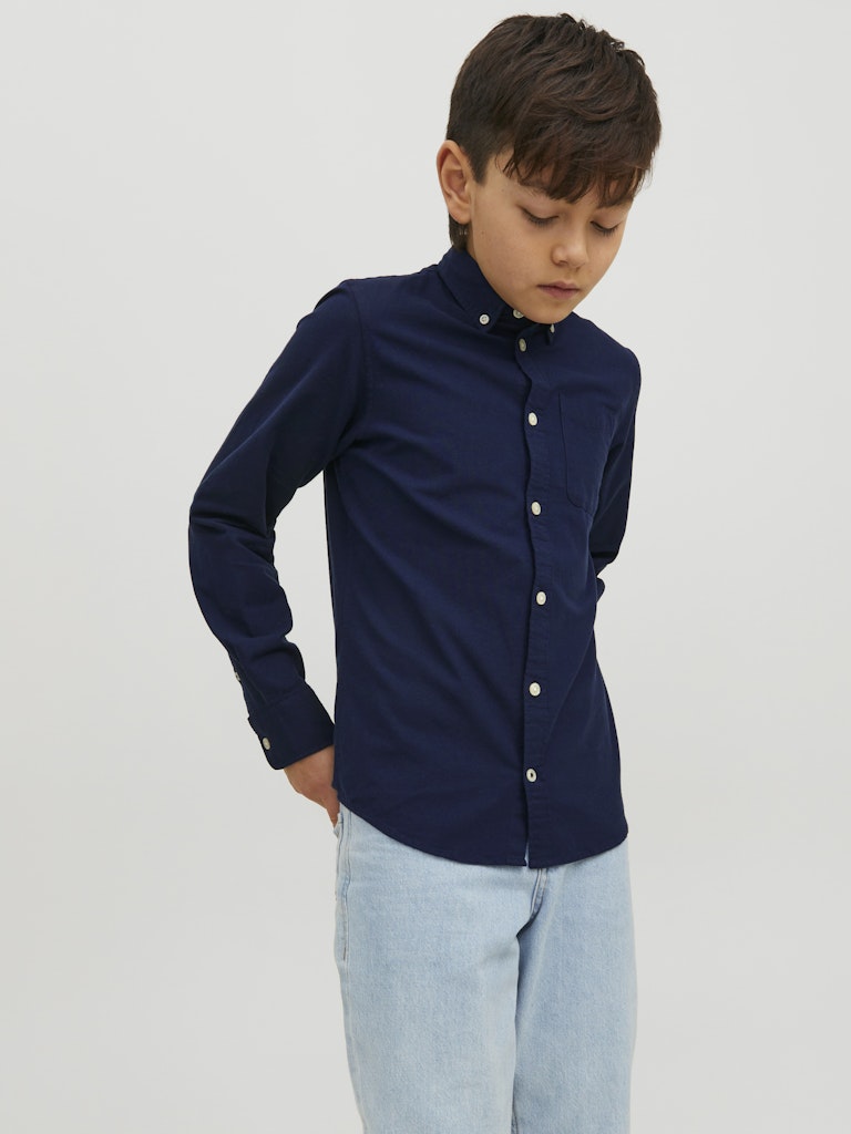 Child wearing a navy shirt and light blue jeans on a plain background