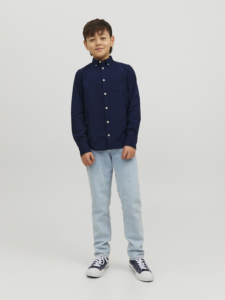 Child wearing a navy shirt and light blue jeans on a white background