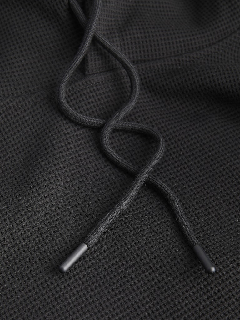 Close-up of black drawstrings on a textured black fabric background