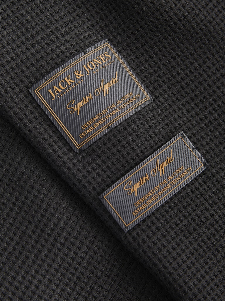 Close-up of Jack & Jones labels on a textured black fabric background