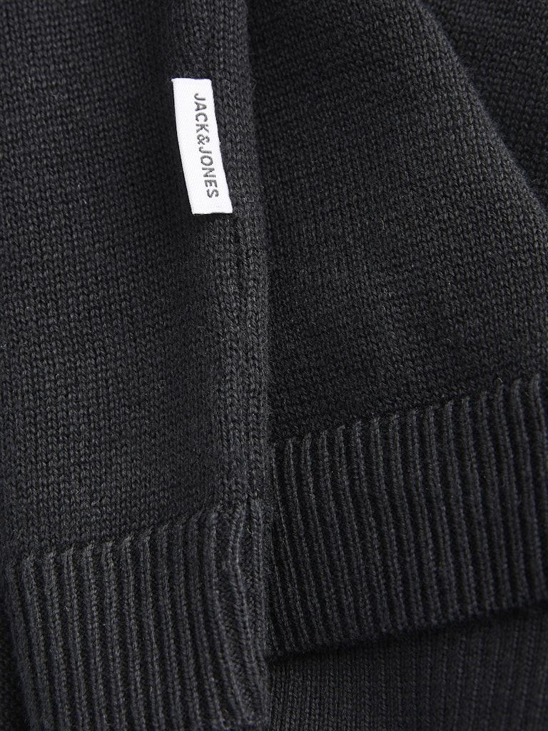 Close-up of a black sweater with a brand label on the side seam.