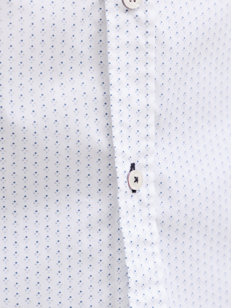 Close-up of a white shirt with small blue dots and buttons.